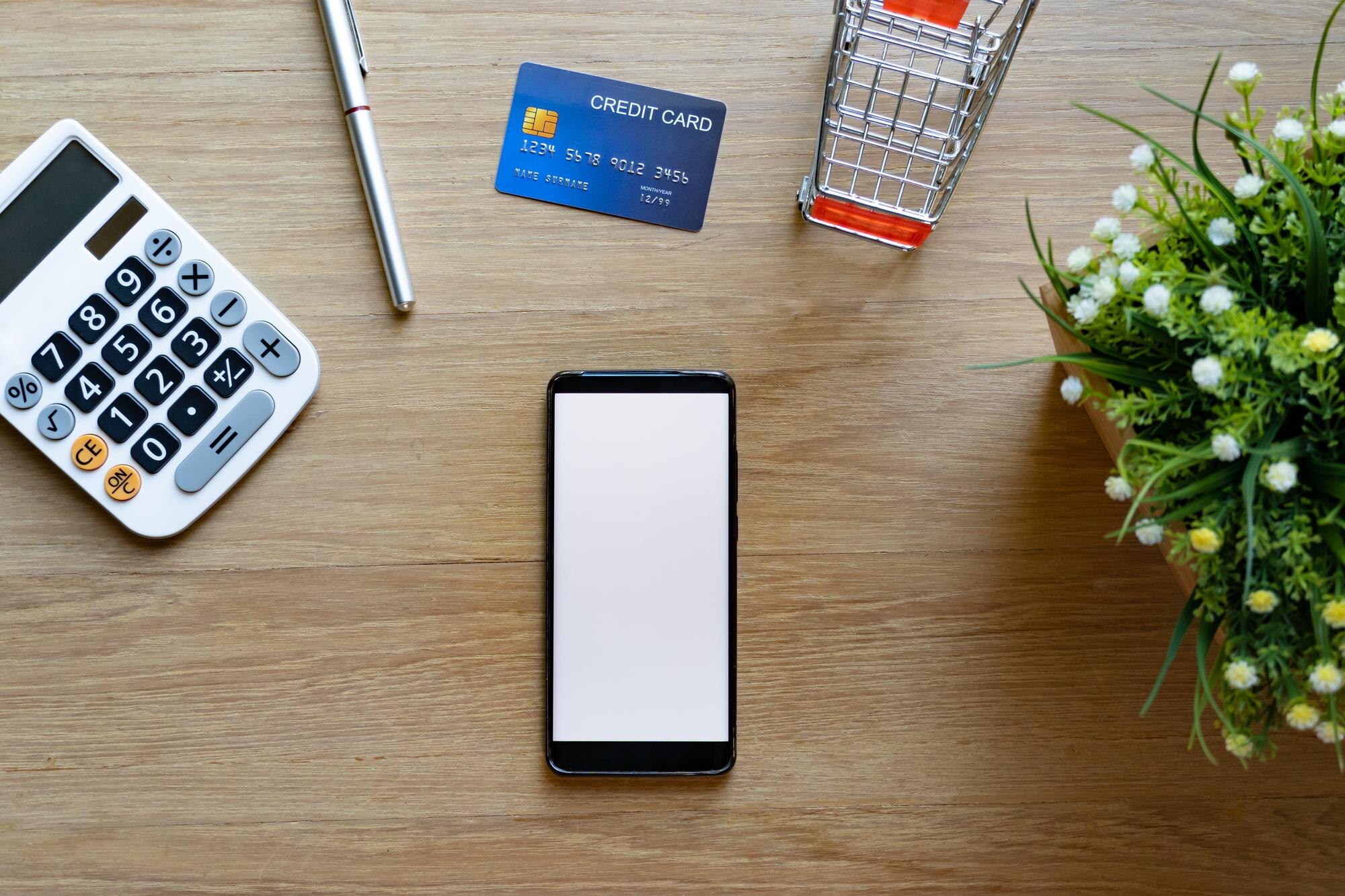 Mobiltelefon, kreditkort och kalkylator som illustrerar automatiska bankbetalningar