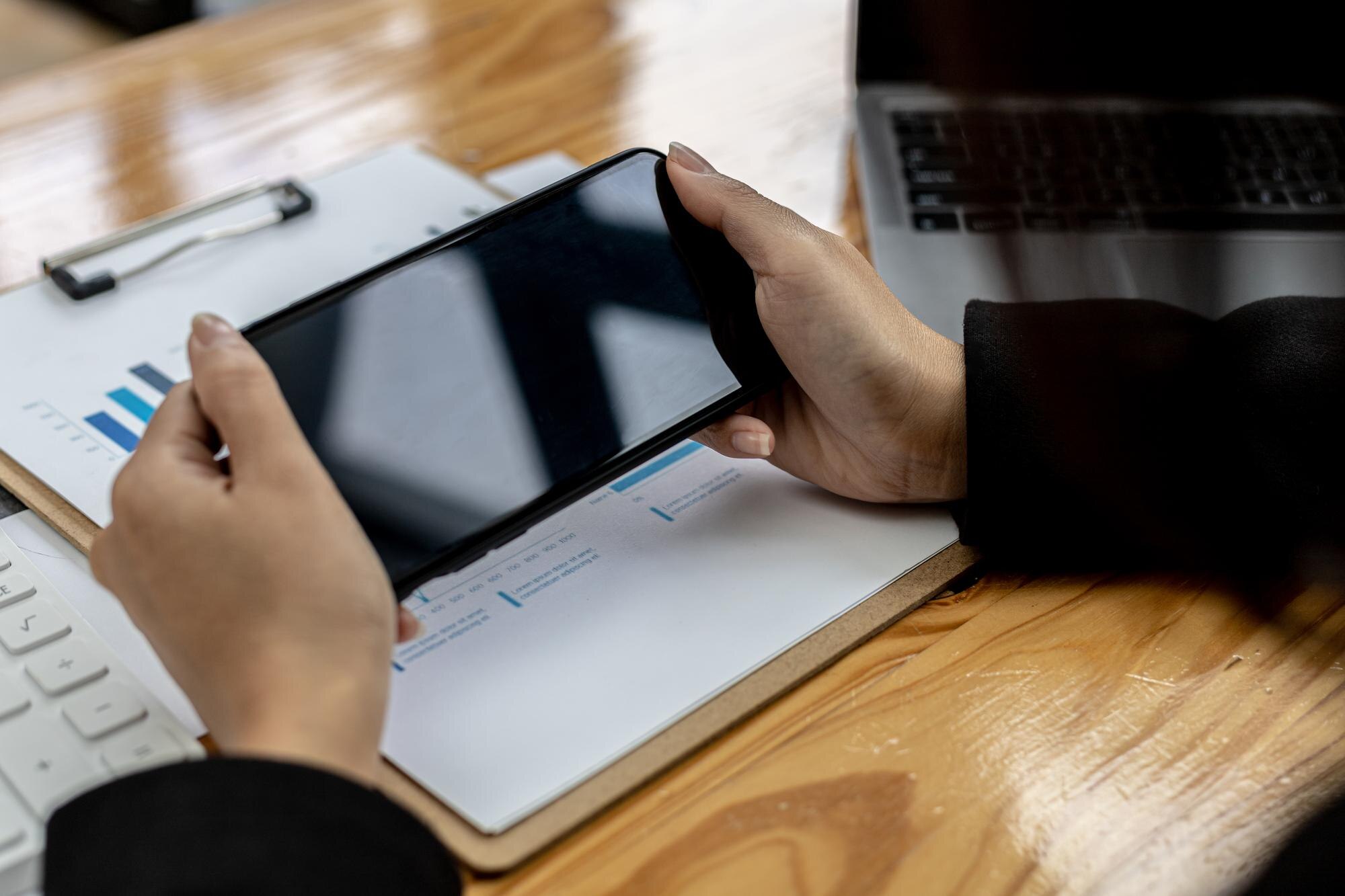 Affärskvinna med smartphone, dokument och laptop som illustration till ändrat bankkonto efter casinouttag