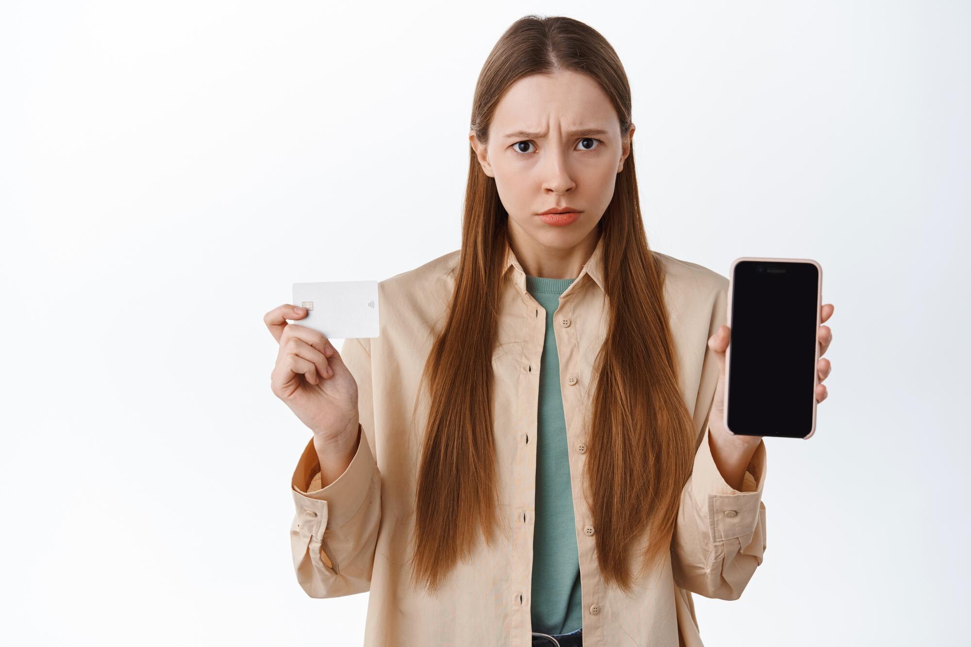 Person som visar smartphone och kort med missnöjd min, som illustration till en casinobonus som tagits bort eller annullerats