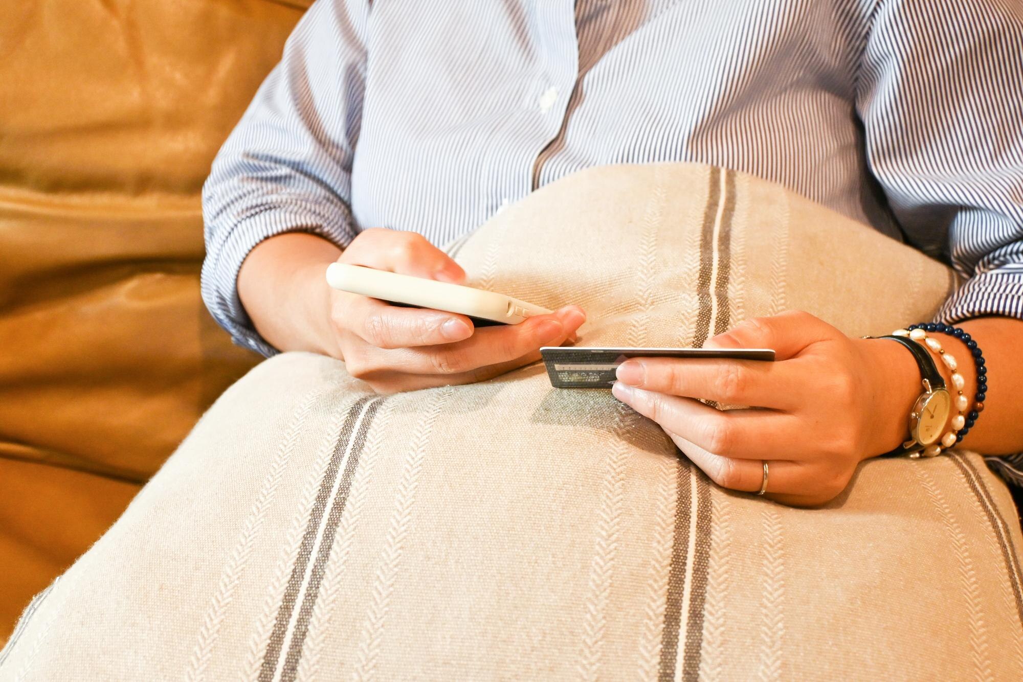 Person som använder smartphone och kort för att kontrollera betalning och saldo, som illustration till låst bonussaldo på casino