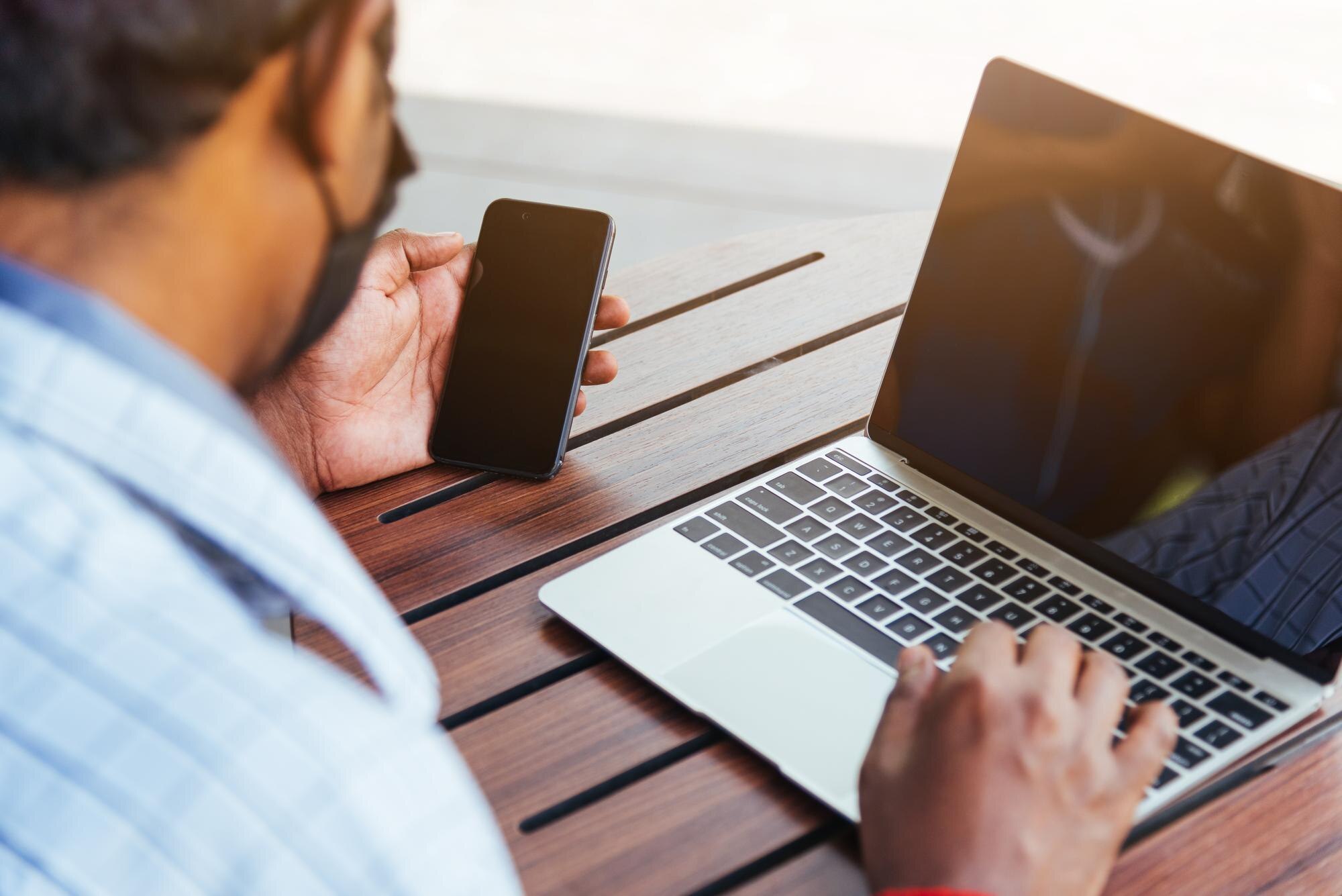 Person som använder smartphone och laptop som illustration till flera registrerade bankkonton på casino