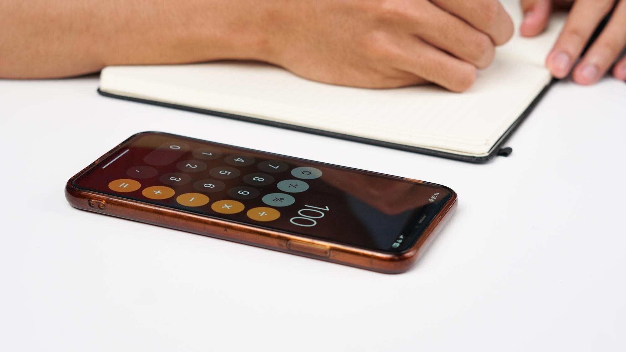 Smartphone och miniräknare med anteckningar som illustration till uttagsavgift på casino