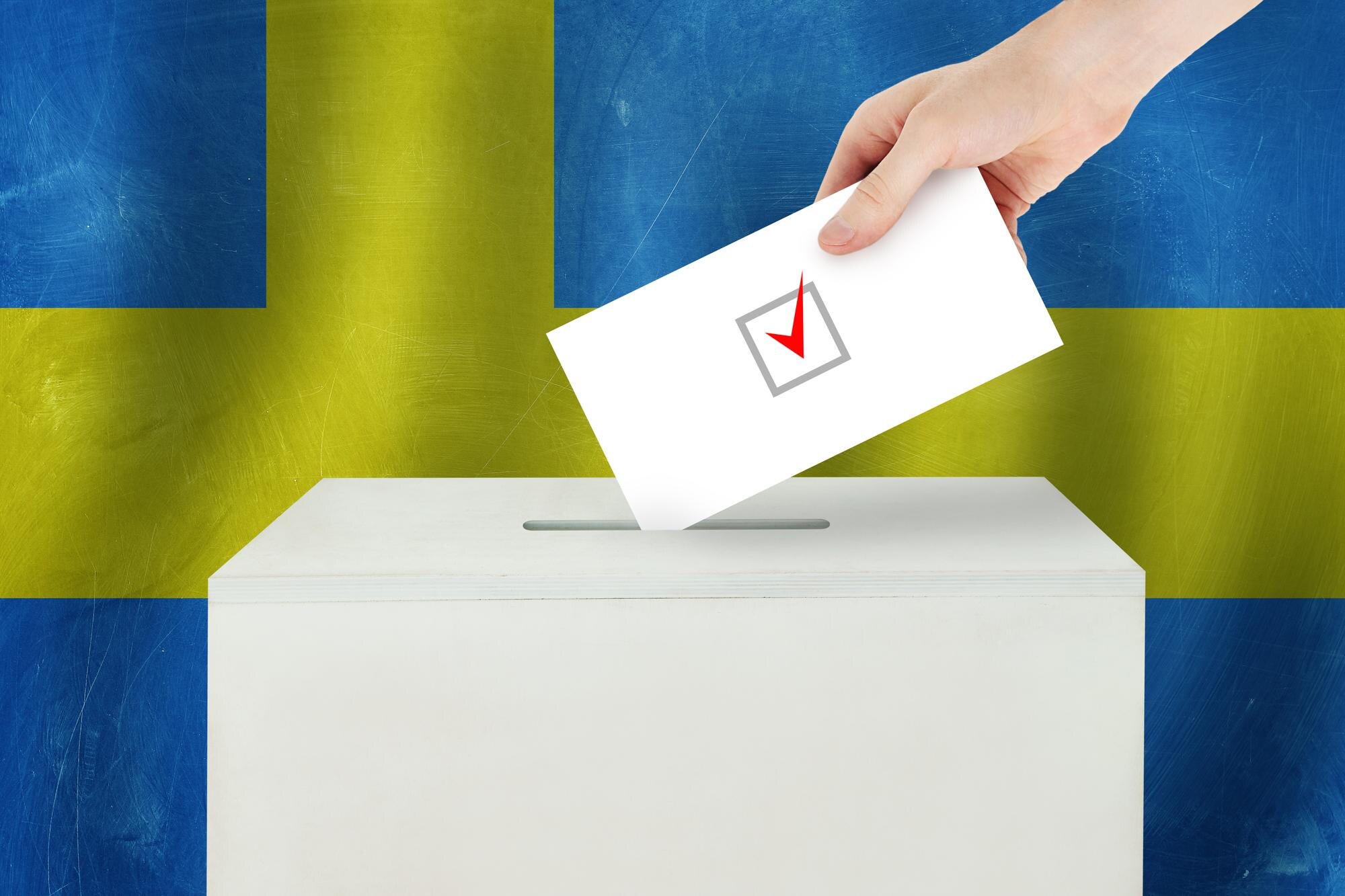 Väljare håller en valsedel vid en svensk vallokal inför valet 2026