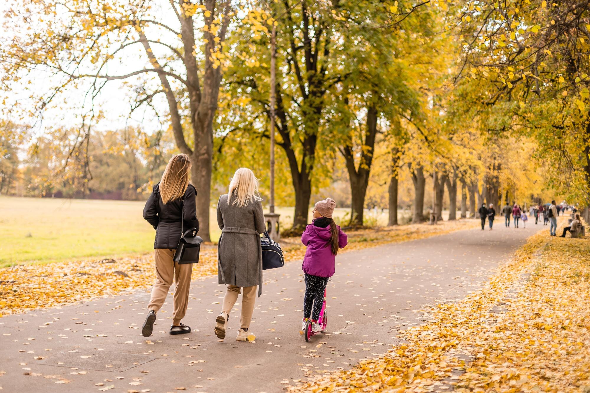 Familj leker bland gula höstlöv i en park som illustration av höstlovsaktiviteter i Stockholm