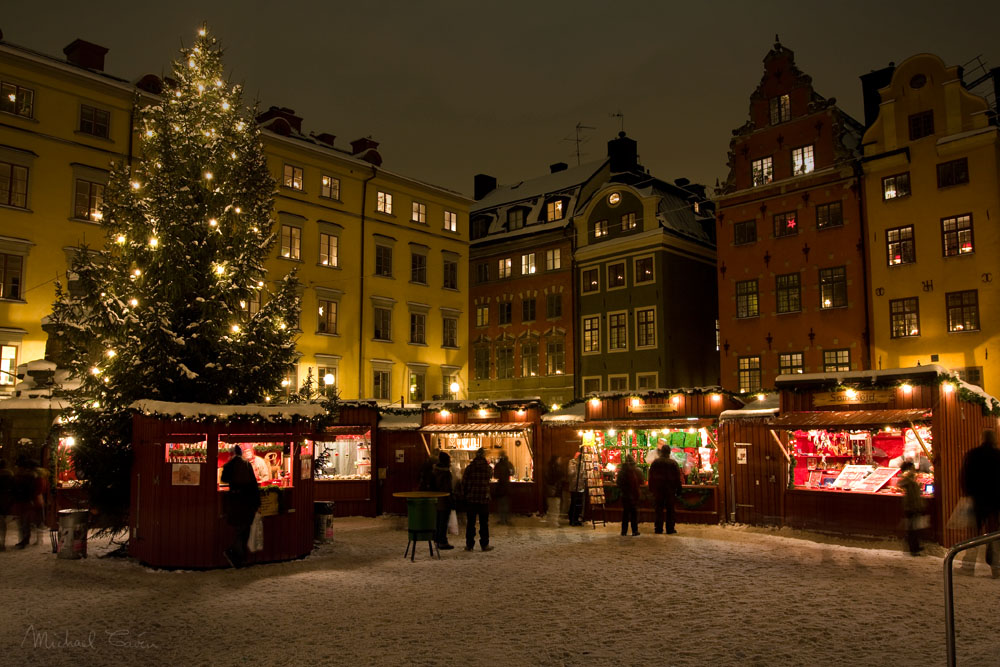 Upplyst julmarknad med röda bodar och julgran på Stortorget i Gamla stan
